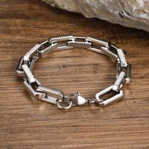 Detail of silver stainless steel chain link bracelet with lobster clasp on rock background