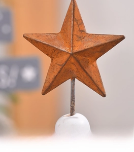 Detail of vintage rusty red iron star ornament with a white circular base in macro view