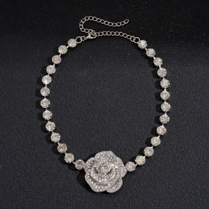 Détail d'un collier avec pendentif fleur argenté orné de strass en cristal brillants