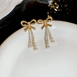 Detail of gold bowknot tassel earrings with clear crystals and white drop pearls
