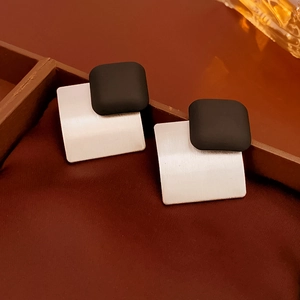 Detail showing matte black square and brushed silver geometric metal earring on silk