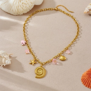 Goldene Edelstahlkette mit Muschel und Seestern Anhängern auf einem Strandhintergrund