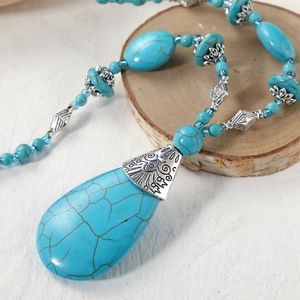 Detail of bohemian turquoise teardrop pendant with vintage silver ethnic engraving