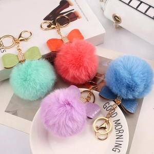 Detail of colorful faux fur pom pom keychains with leather bows and crystal gold clips