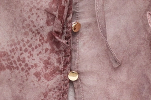 Detailed close-up of pink snake print fabric with a round gold button and soft texture