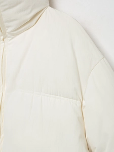 Détail du col montant et des coutures d'épaule d'une doudoune crème pour femmes