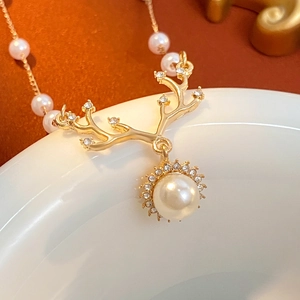 Golden elk antler necklace with a large pearl and zircon accents on a gold chain