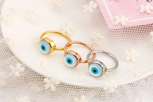 Detailed close-up of a three-piece evil eye ring set in gold, rose gold and silver finish