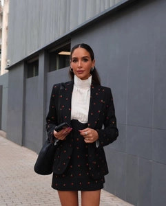 Détail de la broderie fraise rouge sur l'ensemble blazer noir et mini-jupe chic