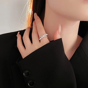 Close-up of elegant crossover pearl ring with silver band worn by a model in black suit