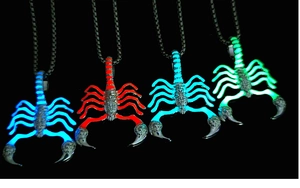 Detailed view of scorpion pendants glowing in blue, red, cyan and green in the dark