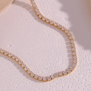 Macro shot of gold-plated square zircon stones on a tennis chain with water droplets