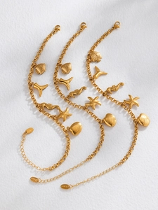 Détail des breloques étoile de mer et coquillage dorées sur bracelet en acier inoxydable