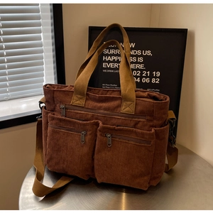 Detail of a brown corduroy tote bag with double front zipper pockets and strap