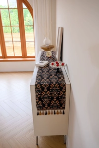 Close-up of floral jacquard table runner with vintage fringes on a marble surface