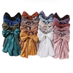 Collection of 14 colorful large satin bow hair accessories in a tidy matrix layout