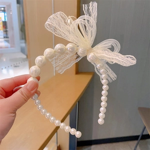 Detailed close-up of ivory lace bow headband with elegant faux pearl chain decoration
