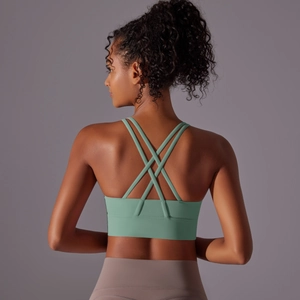 Macro detail of cross-back strap design on sage green yoga sports bra with wide hem