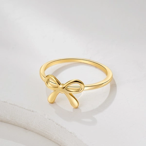 Macro view of 18K gold bow ring on stone base showing polished metallic texture