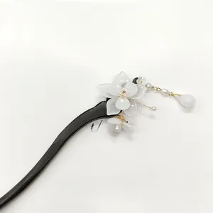 Detail of wooden hair stick with white magnolia flower, pearls and hanging tassels