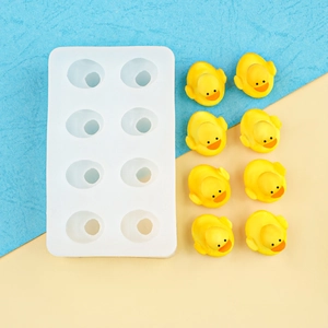 White silicone mold for 8 mini 3D ducks with yellow chocolate ducklings on blue background