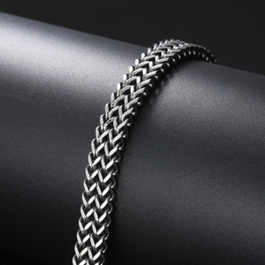 Macro shot of silver stainless steel woven chain links on a cylindrical display stand