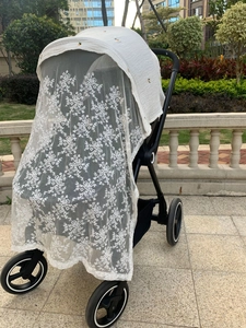 Detail of white lace stroller cover with floral patterns and breathable mesh fabric