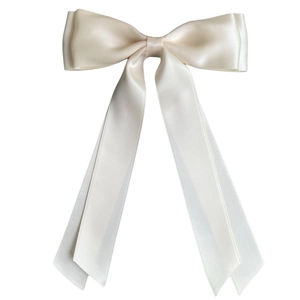 Macro view of cream white double-layered satin bow hair clip with long ribbon streamers