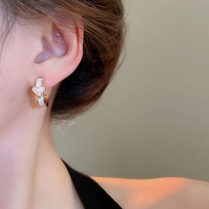 Gros plan de boucles d'oreilles créoles coeur en or portées par un mannequin sous lumière