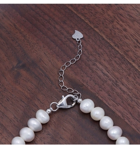 Macro shot of S925 sterling silver lobster clasp with heart charm and white pearls