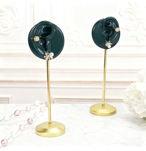 Detail of dark green resin ear mold on gold metal stand for earring display