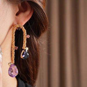Detailed close-up of vintage gold woven earrings with purple and pink crystal tassels