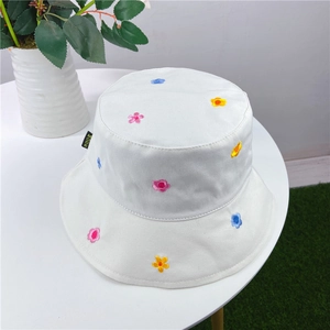 Close-up of white cotton bucket hat featuring colorful flower embroidery and MODE label