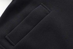 Détail de la poche plate et texture en laine de qualité sur le manteau noir surdimensionné