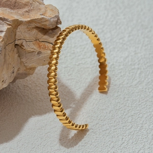 Detail of a gold-plated stainless steel cuff bracelet with a unique ribbed texture finish