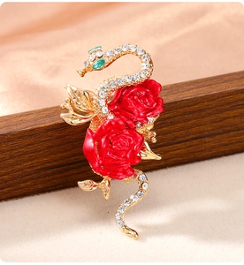 Macro detail of snake brooch with red roses and glittering rhinestones on gold metal