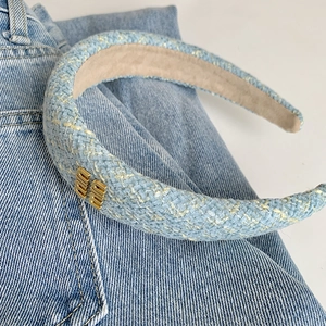 Dettaglio del cerchietto in tweed azzurro con fibbia in metallo dorato su jeans