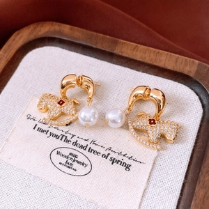 Détail de boucles d'oreilles cheval à bascule 18K avec zircons et perles