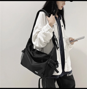 Black nylon crossbody bag on model featuring side mesh pocket and detachable coin pouch