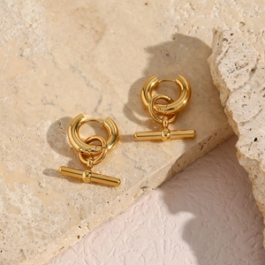 Detailed view of golden hoop earrings with OT toggle clasp on marble background