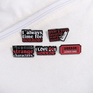 Set of 5 enamel horror movie badges pinned on canvas featuring retro slasher movie quotes