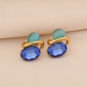 Détail de boucles d'oreilles dorées avec pierre bleue et œil de chat vert rétro