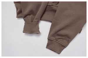 Detailed view of dark brown sweatshirt showing thick ribbed cuffs and hem texture