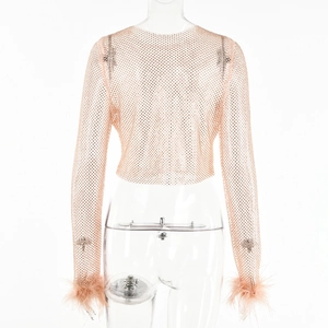 Détail du crop top en maille rose avec strass et poignets en plumes élégants