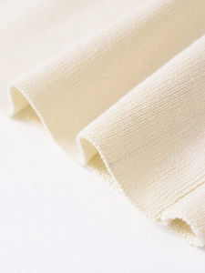 Macro shot of off-white knit fabric showing detailed texture and ribbed weaving pattern