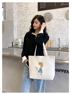 Detail of white canvas tote bag with Nice Day cartoon illustration in a cafe setting
