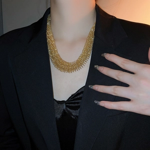 Detail of layered gold metal fringe necklace on a model with black suit