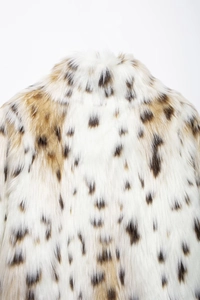 Close-up of white faux fur coat with brown leopard spots and soft long hair texture