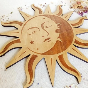Detail of wooden sun wall decor featuring carved face, moon and stars in natural wood tones