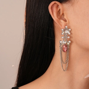 Detail of vintage silver earrings with pink gemstones, pearls, and long metal chain tassels